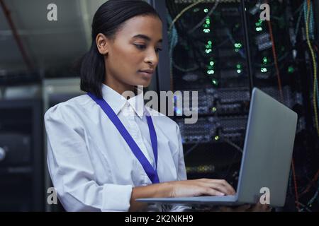 Die Vitalparameter des Servers werden überprüft. Kurze Aufnahme einer attraktiven IT-Support-Agentin, die in einem dunklen Netzwerkserverraum arbeitet. Stockfoto