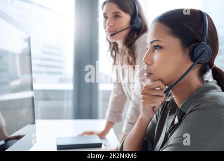 Ich denke, wir müssen uns damit befassen. Aufnahme von zwei Geschäftsfrauen, die in einem Callcenter-Büro zusammenarbeiten. Stockfoto