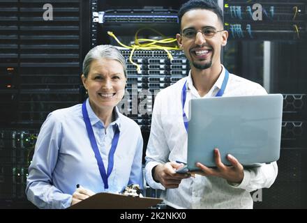 Teamarbeit macht Technologie zum Erfolg. Aufnahme von zwei Technikern, die in einem Serverraum zusammenarbeiten. Stockfoto