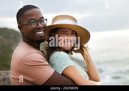 Das Beste am Urlaub ist das Zusammen sein. Aufnahme eines glücklichen jungen Paares, das einen romantischen Urlaub an der Küste genießt. Stockfoto