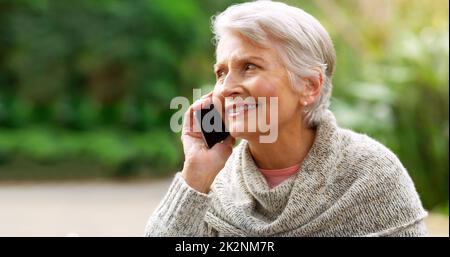 Ich habe diese Sache zum Arbeiten gebracht. Zugeschnittene Aufnahme einer fröhlichen älteren Frau, die draußen in einem Park auf ihrem Handy sprach. Stockfoto