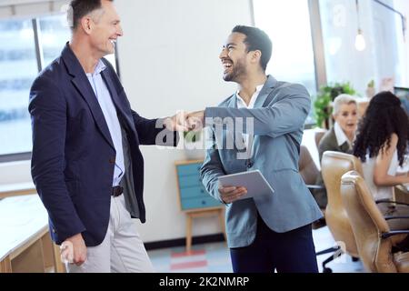 Ich unterstütze Sie. Aufnahme von zwei jungen Geschäftsleuten, die sich bei der Arbeit in einem Büro gegenseitig eine Faustfalle geben. Stockfoto