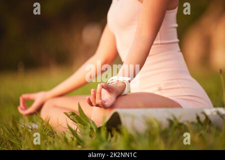 Starker Körper, ruhiger Geist. Ausgeschnittene Aufnahme einer nicht erkennbaren jungen Frau, die an einem sonnigen Morgen draußen meditiert. Stockfoto