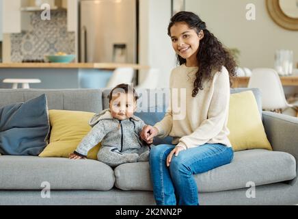Hes der süßeste kleine Junge. Aufnahme einer jungen Mutter, die sich mit ihrem Jungen auf dem Sofa zu Hause anklebte. Stockfoto