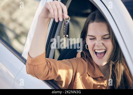 Fahren Sie langsam und genießen Sie die Landschaft. Aufnahme einer Frau, die die Schlüssel zu ihrem neuen Auto vor der Tür hält. Stockfoto