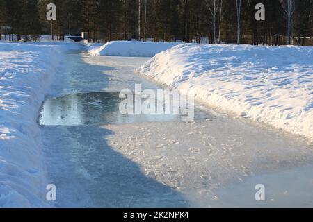 Eine verschneite Straße im Frühling. Schmelzender Schnee. Pfützen. Stockfoto