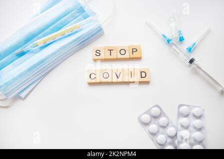 Stoppt die Coronavirus-Inschrift. Vorbereitung zur Impfung gegen Covid-19. Spritze, Impfstoff, Pillen, medizinische Maske. Stockfoto