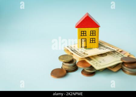 Geld in internationaler Währung, einschließlich Euro, Dollar, eine Münze, auf der sich ein Spielzeughaus befindet. Der Begriff Hypotheken, Investitionen, Kredite, Schulden, Wohnungsbaukäufe: Wohnungen oder Häuser. Stockfoto