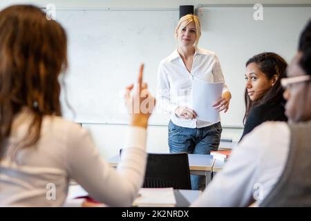 Teenager: Einen Punkt aufwerfen. Eine Schülerin, die eine Frage für ihre Form Tutorin in der Klasse stellt. Aus einer Reihe verwandter Bilder. Stockfoto