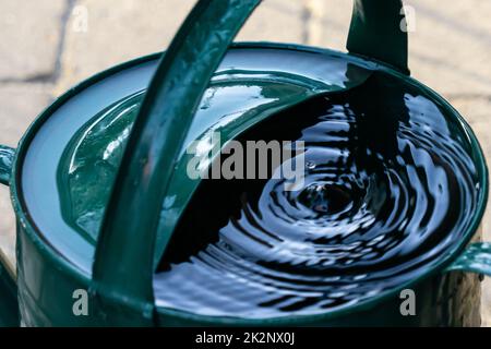 Wasser tropft in eine alte Gießkannte Stockfoto