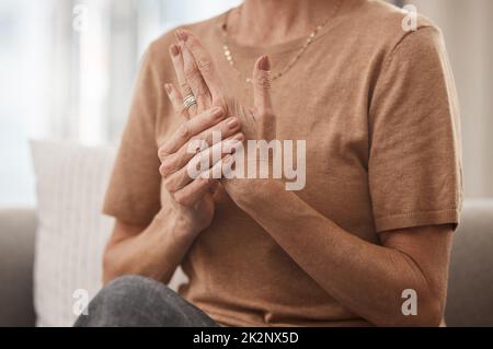 Hilfe, meine Gelenke schmerzten. Aufnahme einer nicht erkennbaren Frau, die zu Hause Schmerzen in der Hand hatte. Stockfoto