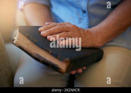 Hierin liegt alle Hoffnung, die Sie brauchen. Nahaufnahme einer älteren Frau, die zu Hause eine Bibel hält. Stockfoto