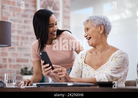 Die intelligente Art, diese Einsparungen zu investieren. Aufnahme einer jungen Frau, die mit ihrer älteren Mutter ein Smartphone benutzt, während sie zu Hause die Finanzen durchläuft. Stockfoto