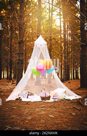 Märchenschloss im Wald. Aufnahme eines Zeltes für eine Kindergeburtsparty, gefüllt mit Luftballons und Geschenken draußen im Wald. Stockfoto