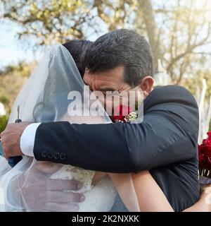 Die Schönheit und Freude des Tages begrüßen. Eine kurze Aufnahme eines Vaters, der seine Tochter an ihrem Hochzeitstag umarmt. Stockfoto