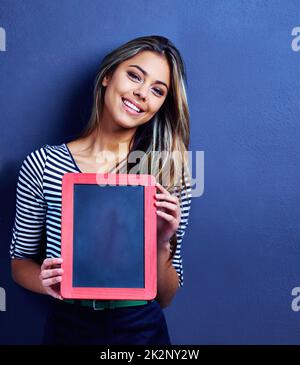 Sie haben eine Nachricht erhalten. Ausgeschnittene Aufnahme einer glücklichen jungen Frau, die eine Tafel in der Hand hält. Stockfoto