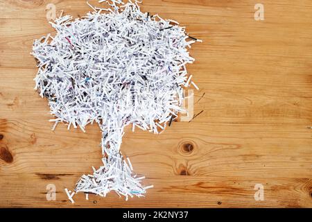 Schonen Sie die Umwelt. Recyceln. Studio Schuss von geschreddertem Papier in der Form eines Baumes auf einem Holztisch angeordnet. Stockfoto