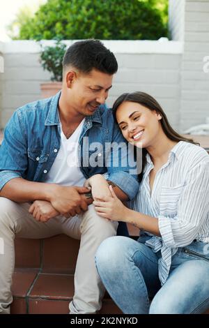 Wahre Liebe. Eine kleine Aufnahme eines anhänglichen jungen Paares, das draußen auf der Terrasse im Hof sitzt. Stockfoto