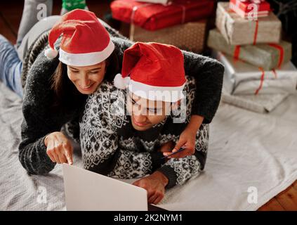 Heute sollte Weihnachten bedeuten, dass wir für morgen glückliche Stunden schaffen. Aufgenommen von einem Paar, das sich zu Hause Filme auf einem Laptop ansieht. Stockfoto