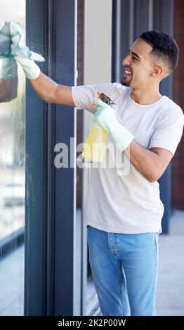 Ich kann es schon durchschauen. Aufnahme eines jungen Mannes, der zu Hause Fenster wascht. Stockfoto