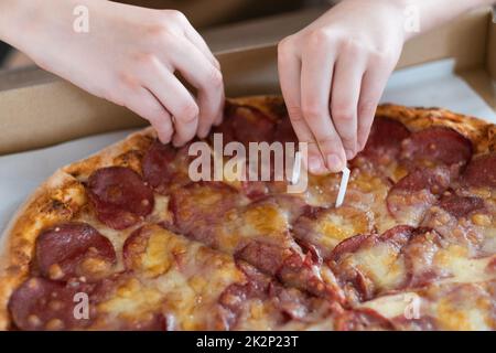 Nahaufnahme der Hand eines Mannes, der eine Scheibe Pepperoni Pizza nimmt. Pizza mit Salami und Käse Stockfoto