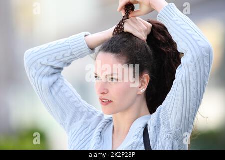 Eine zwanglose Frau, die auf der Straße Pferdeschwanz spielt Stockfoto