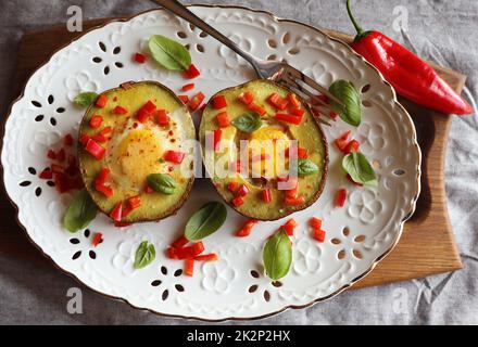 Keto-Diät. Gesundes Frühstück mit gebackenen Avocado- und Eierbooten mit Kräutern Stockfoto