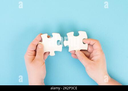 Zwei Puzzleteile in den Händen halten, als Team verbinden und ein Problem-, Strategie- und Kommunikationskonzept lösen Stockfoto