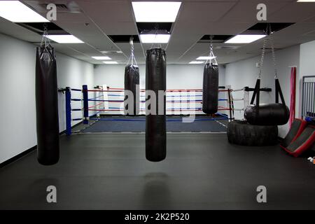 Ein Trainingsraum mit Fitnessraum, Boxsäcken und einem Boxring Stockfoto