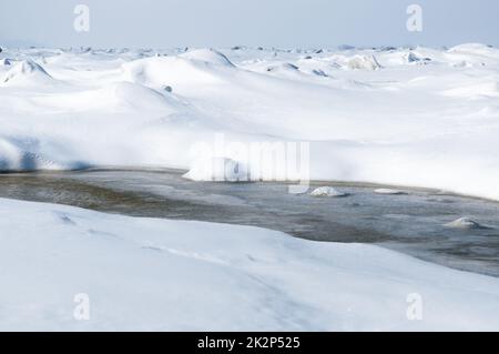 Atemberaubender Blick auf den gefrorenen Fluss bedeckt mit Eisstücken und weißem Frostschnee. Verschneite Wüste. Stockfoto