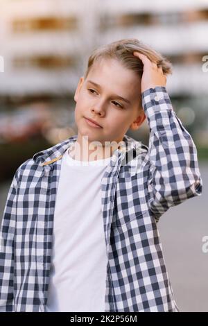 Porträt eines hübschen jungen Mannes in legerer Kleidung. Ein Teenager glättet seine Haare. Stockfoto