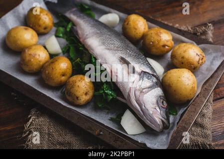 Seebarsch gefüllt mit Sorrel Ready for Baking mit Frühkartoffeln und Zwiebeln Stockfoto