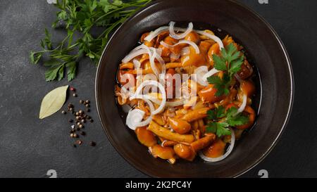 Marinierter Wildhonigpilz Armillaria mellea Pilze mit Gewürzen und Zwiebeln in der Schüssel. Stockfoto