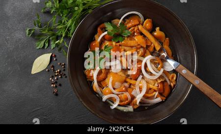 Marinierter Wildhonigpilz Armillaria mellea Pilze mit Gewürzen und Zwiebeln in der Schüssel. Stockfoto