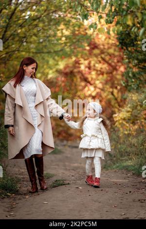 Bezaubernd schöne Mutter geht mit kleinen Tochter Mädchen Stockfoto