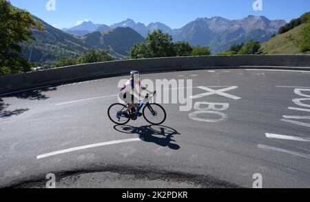 Reife Radfahrerin, die durch die berühmte Kurve 3 auf der Tour de France-Steigung von Alpe d'Huez fährt. Stockfoto