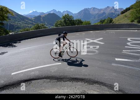 Radsportler, der durch die berühmte Kurve 3 auf der Tour de France-Steigung von Alpe d'Huez fährt. Stockfoto