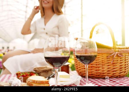 Gläser Primitivo Rotwein mit glücklichem Mädchen im Park auf dem Hintergrund entkoketet. Konzentrieren Sie sich auf Weingläser. Stockfoto