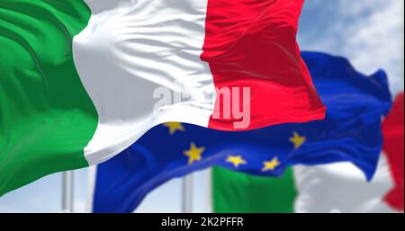 Detail der Nationalflagge Italiens, die im Wind winkt, mit verschwommener Flagge der europäischen Union im Hintergrund an einem klaren Tag Stockfoto