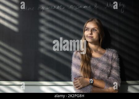 Hübsche, junge Schülerin vor einer Tafel während der Klasse Stockfoto