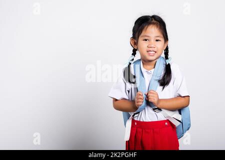 Asiatische liebenswert Kleinkind lächelnd glücklich tragen Student thai uniform roten Rock stehen Stockfoto