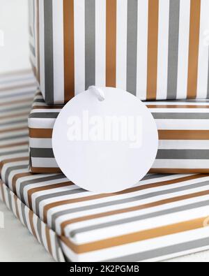 Geschenke in gestreiftes Papier eingewickelt mit leerem Geschenkanhänger Nahaufnahme, Label Mockup Stockfoto