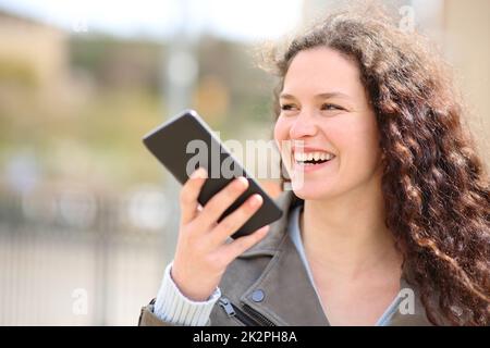 Glückliche Frau, die mit Spracherkennung am Telefon lacht Stockfoto