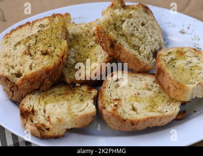 Baguette-Scheiben mit Knoblauch und Olivenöl auf einem weißen Teller Stockfoto