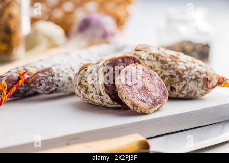 Traditionelle Wurst mit weißem Schimmel. Getrocknete Schweinesalami auf dem Schneidebrett. Stockfoto