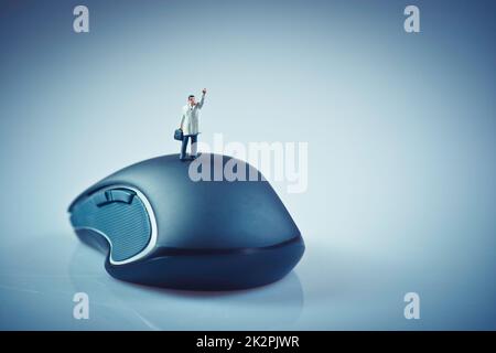 Ein kleiner Geschäftsmann, der auf einer Computermaus winkt. Geschäftskonzept Stockfoto