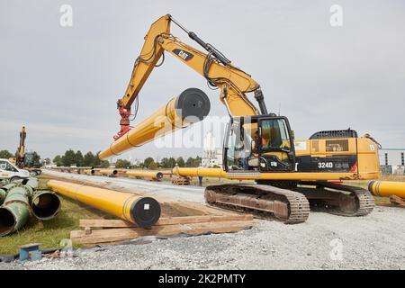 23. September 2022, Schleswig-Holstein, Brunsbüttel: Ein Kran transportiert ein Rohr mittels einer Vakuumrichtung auf die Baustelle der Pipeline für den geplanten schwimmenden Flüssiggas-Terminal. Foto: Georg Wendt/dpa Stockfoto