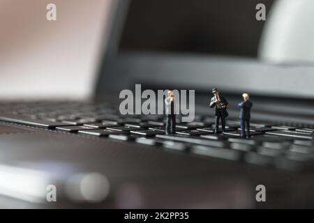 Miniatur-Geschäftsleute stehen auf Laptop-Tastatur Stockfoto
