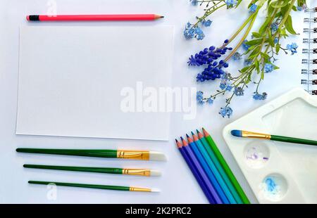 Flaches Skizzenbuch und pinkviolette, blaue, violette und grüne Bleistifte auf weißem Hintergrund. Künstlerische Tischansicht von oben Stockfoto
