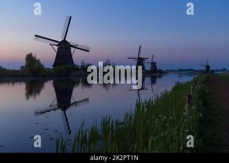 Traditionelle niederländische Windmühlen mit einem bunten Himmel kurz vor Sonnenaufgang in Kinderdijk, Niederlande Stockfoto
